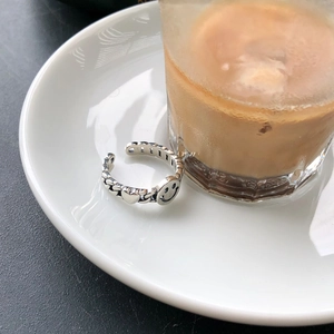 Detail of S925 sterling silver smile and heart embossed ring on a ceramic plate