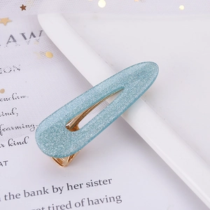 Detailed close-up of a blue glitter acetate teardrop hair clip with a golden metal base