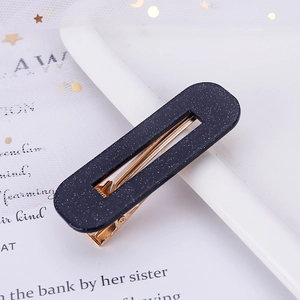 Detail of a rectangle black acetate hair clip with silver glitter and gold metal spring