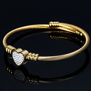 Macro shot of 11mm gold cable wire bracelet with shimmering diamond heart charm