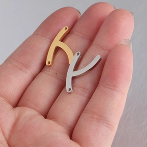 Detail of wishbone pendants in gold and silver held in palm for scale and size