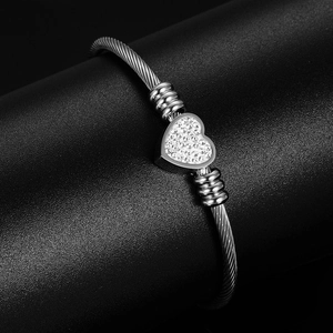 Macro shot of silver stainless steel cable bangle with a pavé heart crystal detail