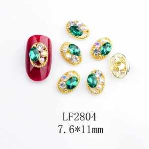 Detailed view of emerald glass nail art jewel with gold frame and mini pearl accent