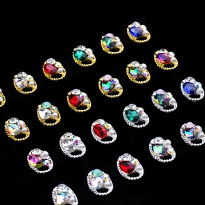 Detailed close-up of oval crystal nail charms with small pearls and gems on black velvet