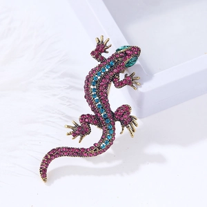 Macro detail of lizard brooch with pink crystals and turquoise stones on gold base