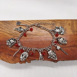 Détail macro du bracelet à breloques argenté avec masques d'horreur sur bois texturé
