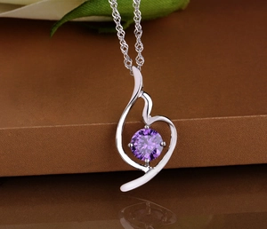 Macro detail of silver necklace featuring a purple zircon gemstone and flowing design