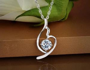 Macro detail of silver necklace pendant featuring interlocking curves and a large round zircon