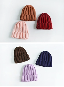 Detail view of ribbed knit beanies in multiple colors like brown, red, and navy blue