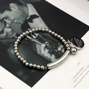 Polished bead titanium steel bracelet with engraved round pendant on fashion magazine