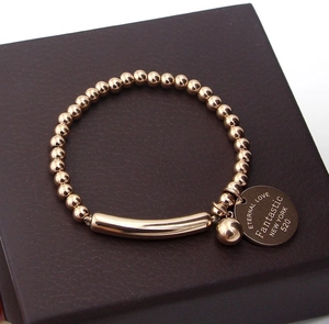 Detail of rose gold bead bracelet with curved bar and Eternal Love engraved coin charm