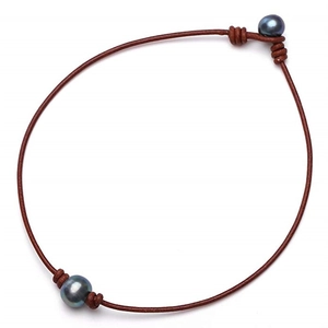 Detail of genuine brown leather cord necklace with two dark lustrous large pearls