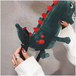 Detail of green plush dinosaur crossbody bag featuring soft texture and red accents