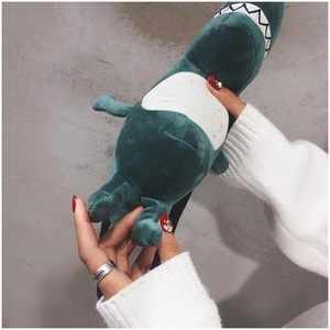 Close-up of a plush green dinosaur crossbody bag with soft texture and white belly details