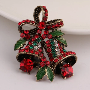 Macro detail of Christmas bell brooch with red enamel, crystals and green holly leaves
