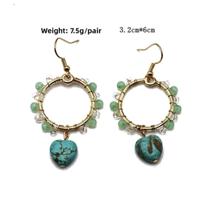 Detailed view of gold hoop earrings with turquoise heart pendants and beaded fringe design