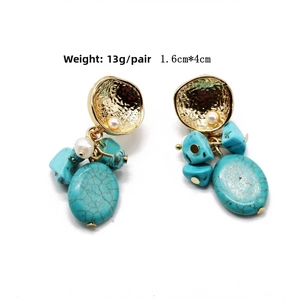 Detailed view of turquoise bohemian drop earrings with gold hammer texture and pearls