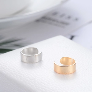 Minimalist U-shaped cuff earrings in gold and silver finish shown on textured background