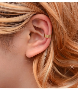 Close-up of minimalist golden U-shaped ear cuff showing smooth metallic finish on ear