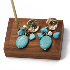 Macro shot of vintage gold earrings featuring turquoise stones and faux pearl details