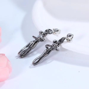 Artistic gunmetal hug earrings with abstract flowing lines on a white ceramic tray