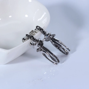 Close-up of artistic silver hugging figure earrings hanging on a white ceramic display