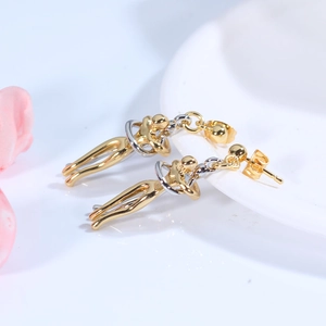 Artistic hug shaped earrings with gold and silver two-tone plating on a ceramic tray