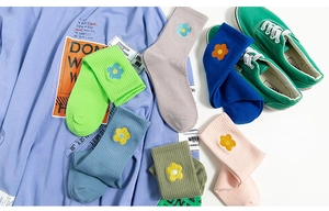 Detail of colorful knitted mid-calf socks featuring delicate floral embroidery and ribbed texture