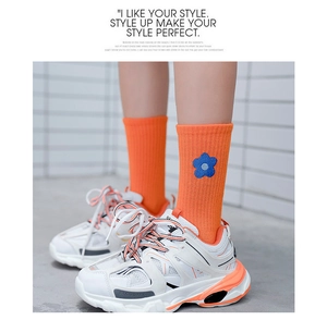 Detailed close-up of orange cotton crew socks featuring delicate blue floral embroidery