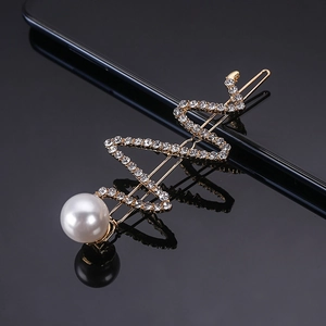 Macro detail of a snake-shaped hair clip with pearls and rhinestones on a gold base