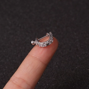 Macro shot of stainless steel screw stud earring with zircon inlay held on finger