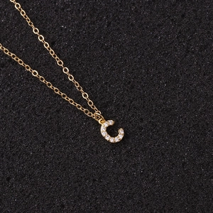 Macro detail of golden letter C pendant with sparkling zircons on a classic O-chain
