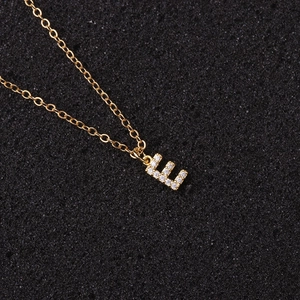 Detailed macro shot of gold letter E necklace pendant with sparkling zircon inlays