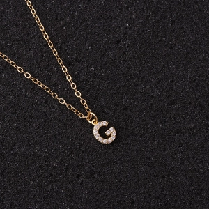 Macro detail of golden letter G pendant with inlaid zircons on a fine O-link chain