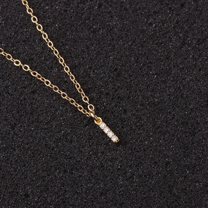 Macro shot of gold zircon necklace with a sparkling vertical bar pendant on black