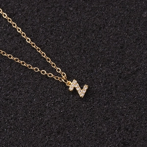 Macro detail of gold letter Z pendant with micro-pave zircon on simple link chain