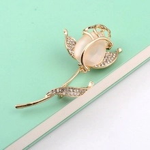 Macro shot of gold rose brooch with frosted opal bud and sparkling rhinestones