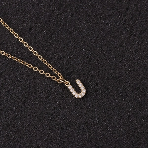 Close-up of golden necklace featuring a zircon-studded letter U pendant on a fine chain