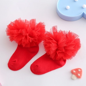 Nahaufnahme von roten Mädchensocken mit flauschigen Spitzen-Pompons und Rüschendetails