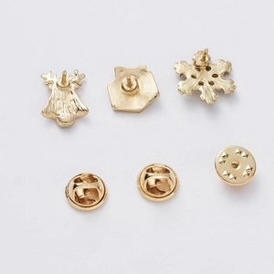 Detailed back view of gold Christmas brooches showing butterfly clutch pin and textured finish