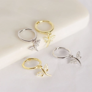 Macro detail of silver and gold dragonfly hoop earrings with sparkling cubic zirconia
