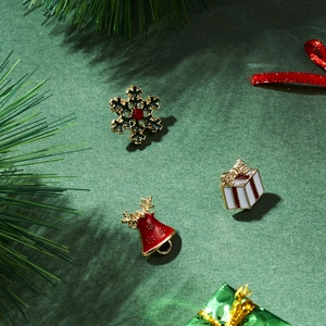 Detail of Christmas enamel brooches featuring snowflake and reindeer on pine background