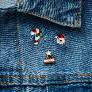 Close-up of three Christmas enamel pins featuring Santa and trees on denim jacket