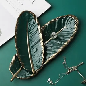 Detail of dark green ceramic feather tray with gold edge for jewelry storage and decor