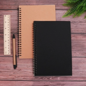 Flat lay of vintage A5 spiral notebooks in kraft and black paper with matching pens