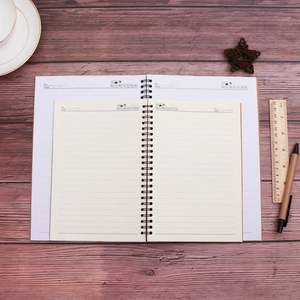 Top view of spiral kraft notebooks in two sizes on dark wood with stationery tools