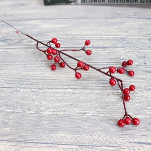 Artificial red berry stems on light wood background for Christmas home decoration