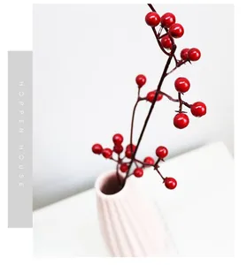 Macro shot of artificial red berries in a pink ceramic vase with a white background