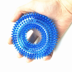 Blue spiked TPR dog chew ring toy for aggressive chewers being held in hand for size comparison