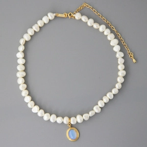 Detail of freshwater pearl necklace with light blue gemstone oval pendant on gray background